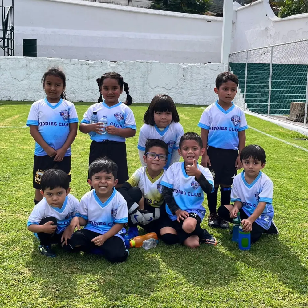 Equipo de fútbol de Kiddies Club posando en la cancha con su uniforme celeste