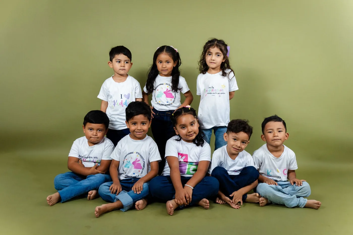 Grupo de pequeños de Kiddies Club posando juntos con sus camisetas de Kiddies en una sesión de fotos