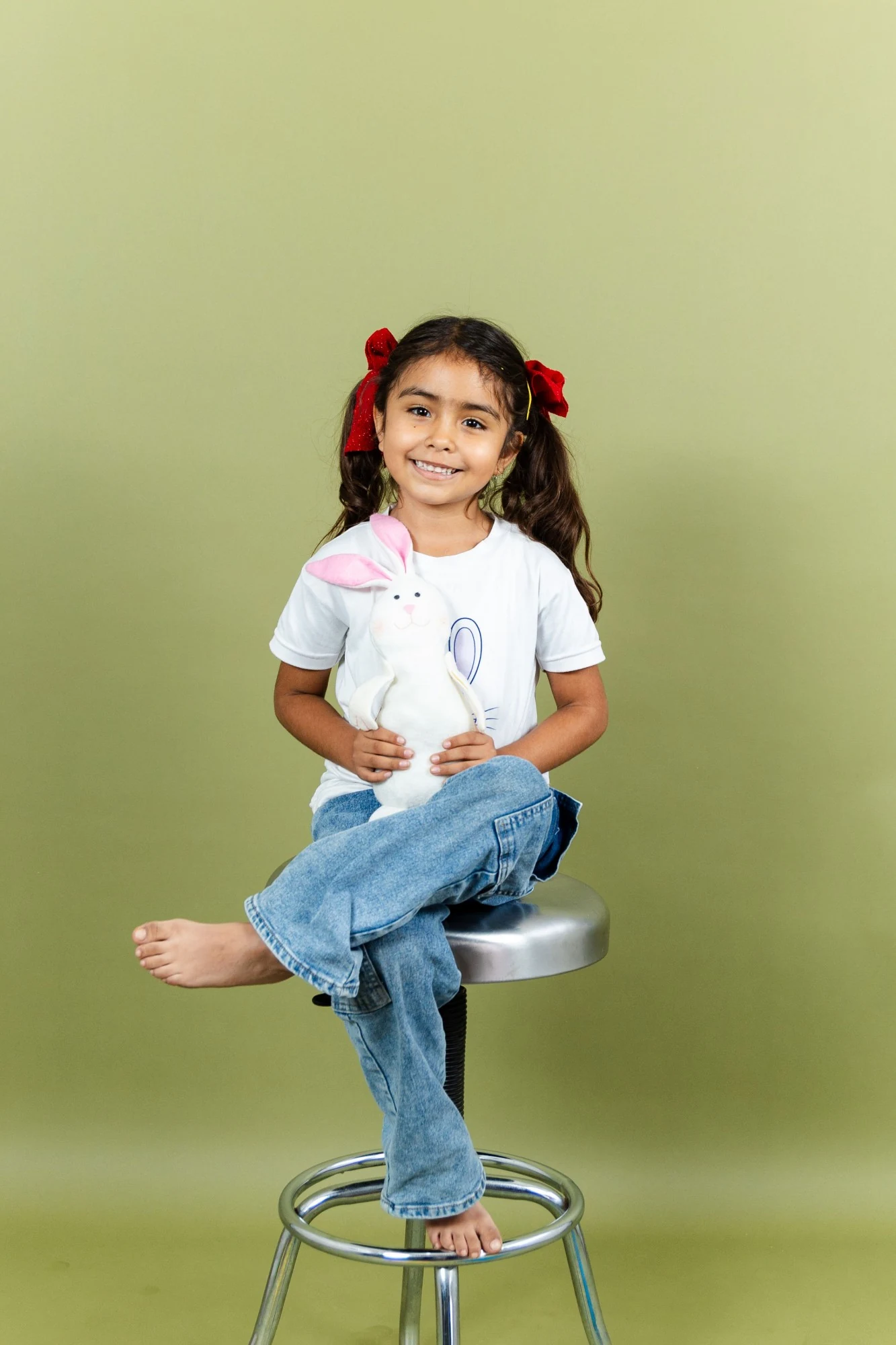 Niña de Preprimaria sonriendo sentada con un conejito de peluche